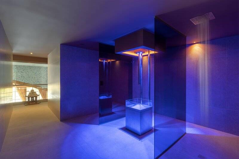 Ein modernes Badezimmer mit blauer Beleuchtung und einer Dusche im Royal Savoy Hotel.