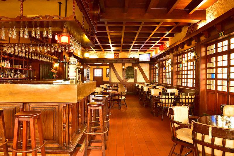 Innenansicht der Bar im Pestana Carlton Madeira Hotel mit Holzmöbeln und getrimmten Decken.