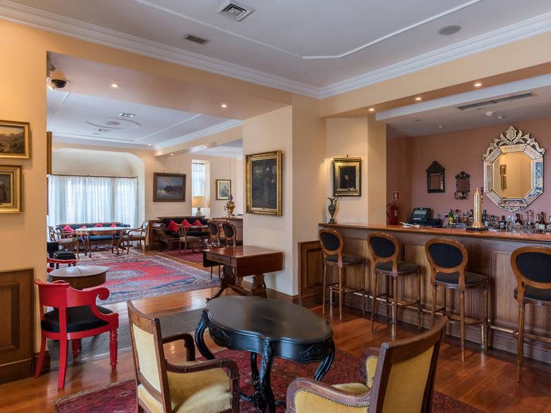 Innenansicht der Bar im Pestana Miramar Garden & Ocean Resort mit Barhockern, Tischen und Dekor.