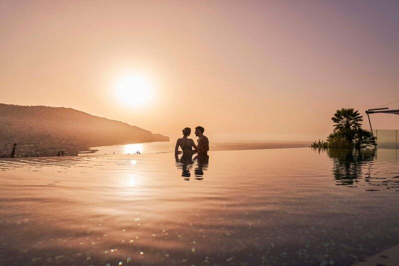 Ein Paar genießt den Sonnenuntergang im Infinity-Pool des Savoy Palace.