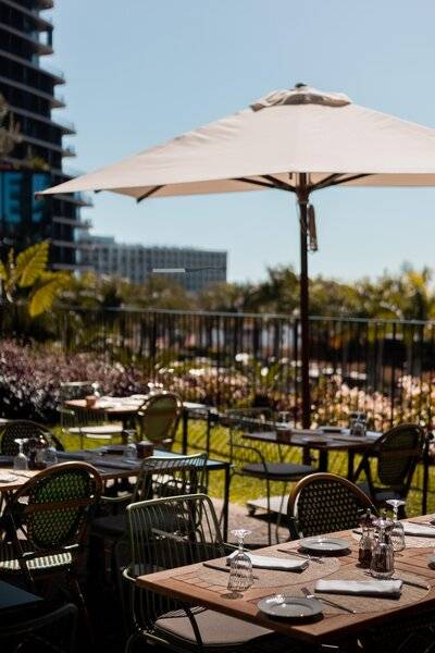 Gartenrestaurant des Savoy Palace Hotels mit Tischen und Stühlen unter einem Schirm.