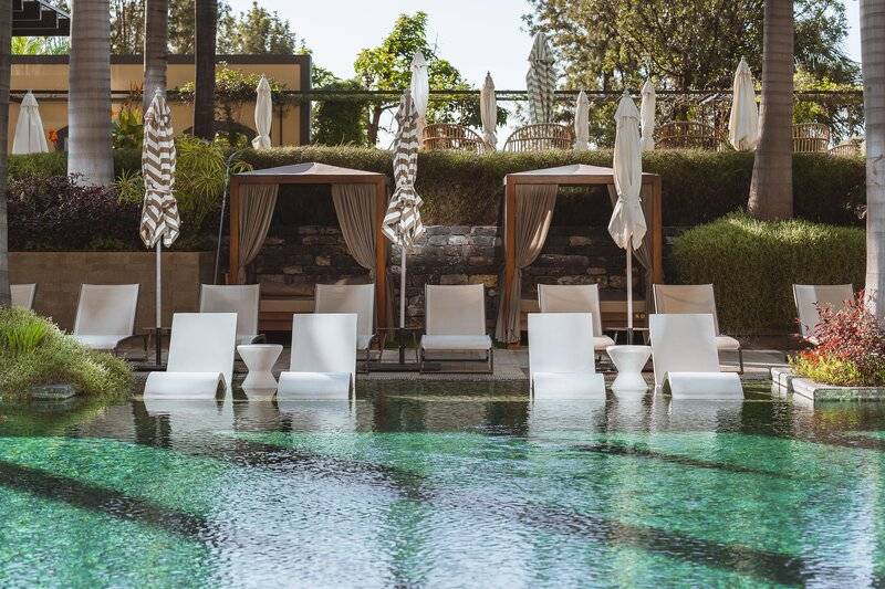 Pool-Lounge-Bereich im Savoy Palace Hotel mit weißen Liegestühlen und Sonnenschirmen.
