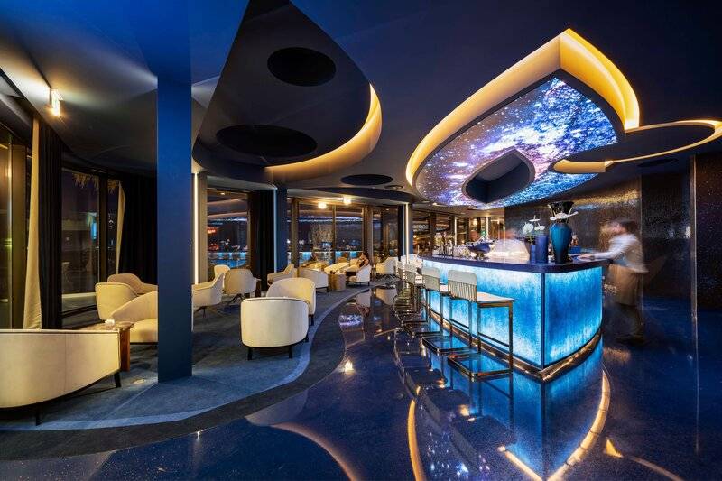 Innenansicht der Bar im Savoy Palace Hotel mit blauer Beleuchtung und modernen Möbeln.