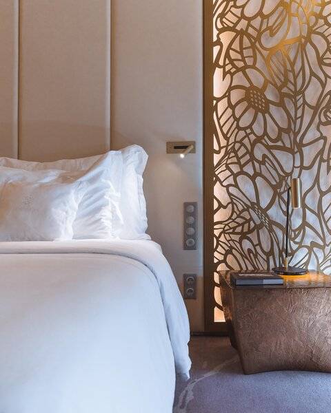 Schlafzimmer im Savoy Palast Hotel mit weißem Bett und goldenem Wandpaneel
