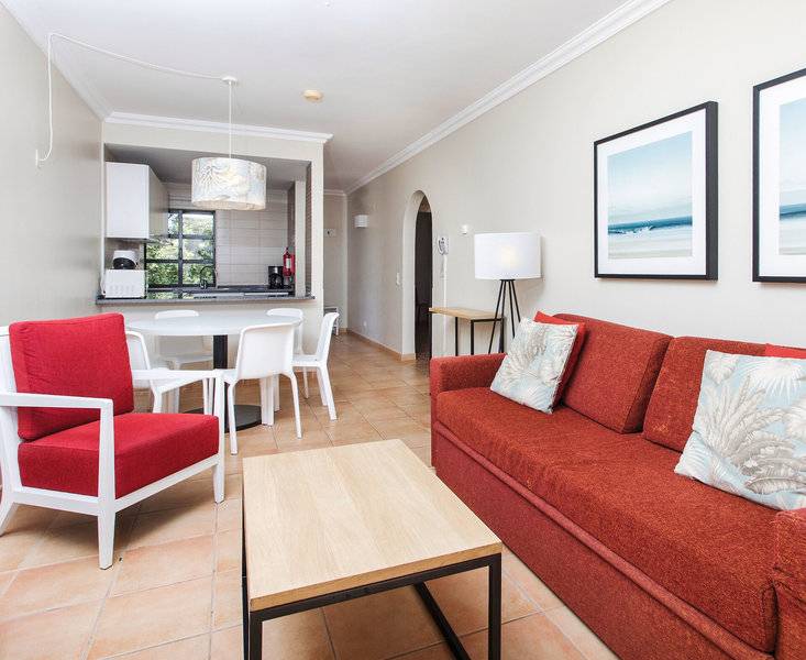 Wohnzimmer mit rotem Sofa, weißen Stühlen und Tisch im Alfagar Village