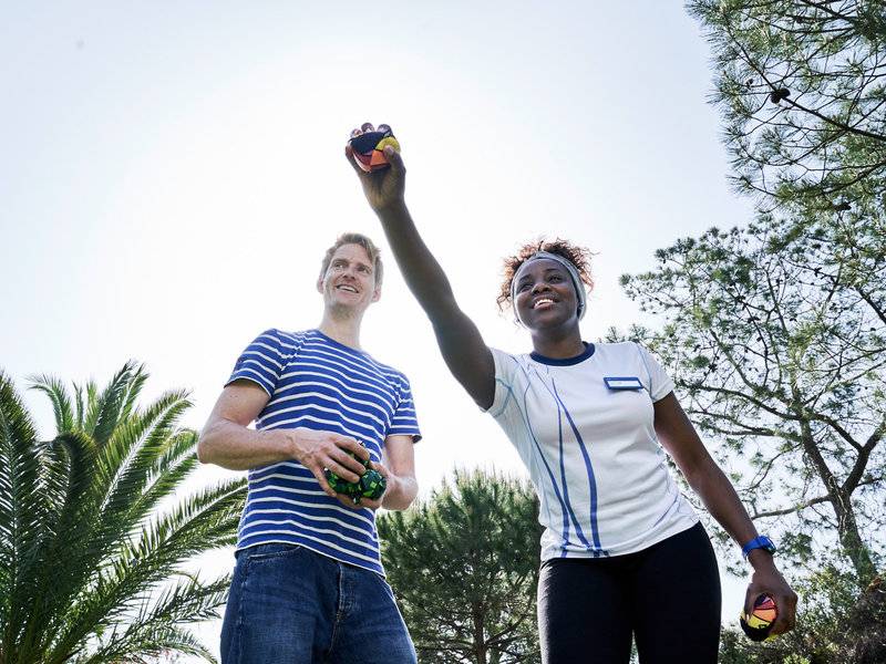 Zwei Personen, eine Frau und ein Mann, spielen mit bunten magischen Würfeln in einem Garten.