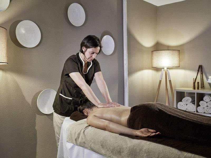 Eine Frau im schwarzen Outfit führt eine Massage in einem Raum des Falesia Hotels im Algarve durch.
