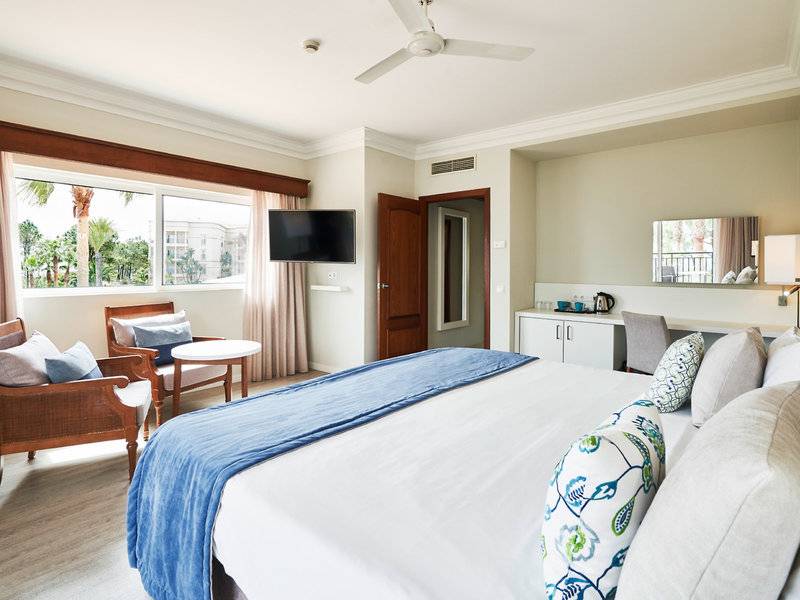 Innenansicht eines Zimmers im Falesia Hotel - Algarve mit Bett, Fernseher und Fenster.