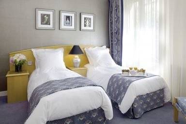 Doppelbettzimmer im Les Jardins du Marais Hotel mit zwei Betten, Nachttischen, Lampen und drei gerahmten Bildern an der Wand.