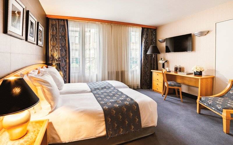 Hotelzimmer von Les Jardins du Marais mit zwei Betten, Schreibtisch und Fernseher.