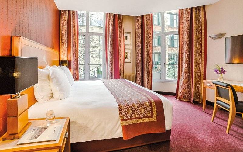Schlafzimmer des Les Jardins du Marais Hotels mit großem Bett, Fenstern und Dekor.