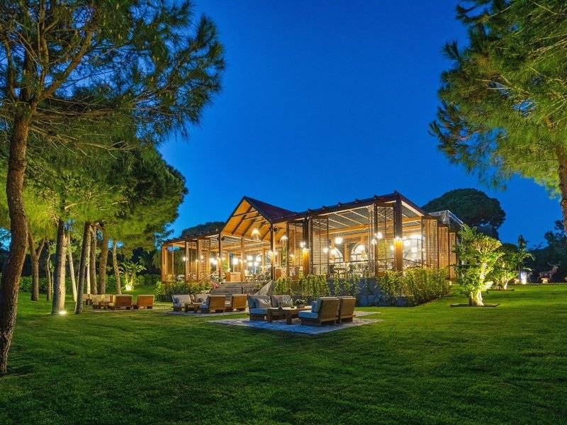 Außenbereich des Rixos Premium Belek Hotels bei Nacht mit Beleuchtung und Möbeln im Freien