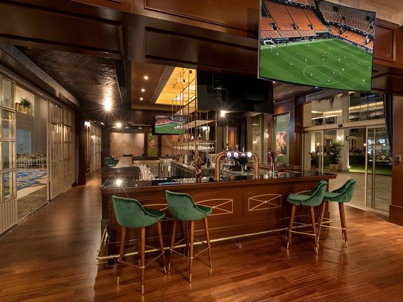 Innenansicht der Bar im Rixos Premium Belek Hotel mit grünen Stühlen und Fernseher