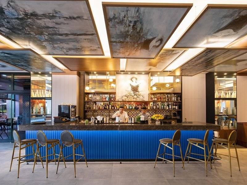 Innenansicht der Bar im Rixos Premium Belek Hotel mit Barkeepern und Kunden.