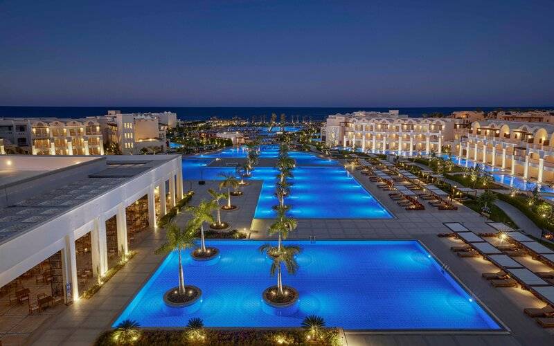 Luftaufnahme des Steigenberger Resort Alaya mit beleuchtetem Swimmingpool und Sonnenliegen