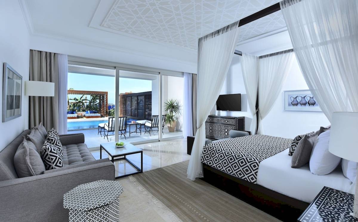 Hotelzimmer mit Bett, Sofa und Blick auf den Pool im Steigenberger Resort Alaya.