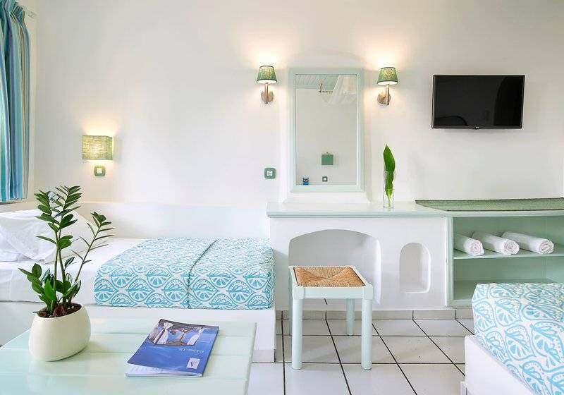 Innenansicht eines Zimmers im Mitsis Cretan Village Hotel mit zwei Betten, einem Fernseher und einem Tisch.