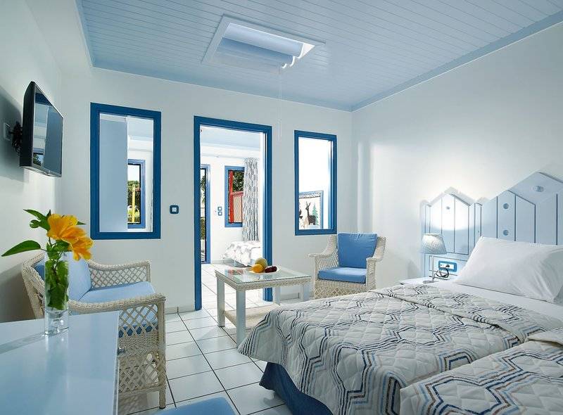 Doppelzimmer im Mitsis Cretan Village Hotel mit blauen Akzenten und weißen Möbeln.