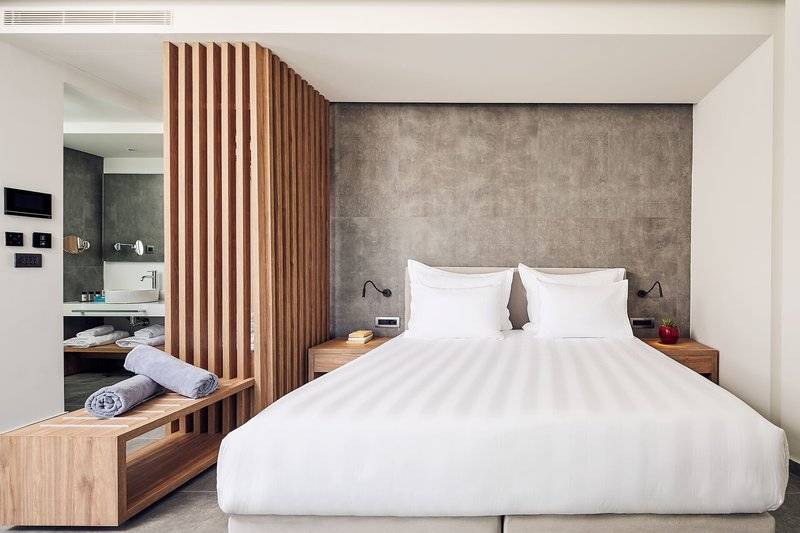 Schlafzimmer im Lindos Grand Resort & Spa mit weißem Bett und grauer Wand