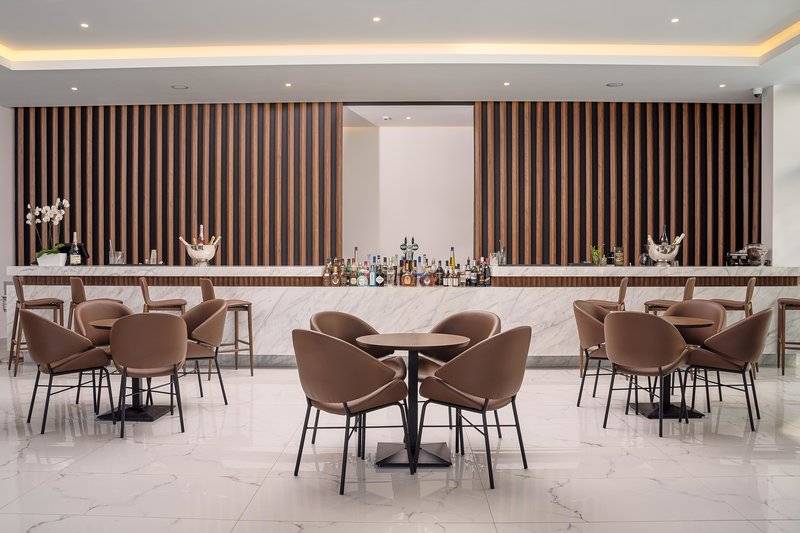 Innenansicht der Bar im Lindos Grand Resort & Spa Hotel mit gemusterten Wänden und modernen Möbeln.