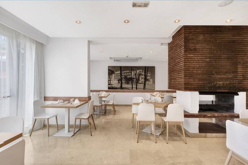 Innenansicht des Restaurants im THB Gran Playa Hotel mit weißen Möbeln und einem großen Foto an der Wand.