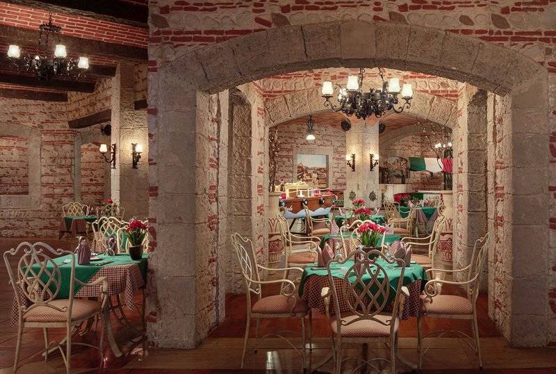 Innenansicht des Restaurants im Palm Royale Soma Bay Hotel mit Steinwänden und grünen Tischdecken.