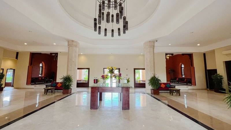 Lobbybereich des Gemma Resorts mit einer großen Holztisch, Blumen, hohen Decken und Kronleuchter