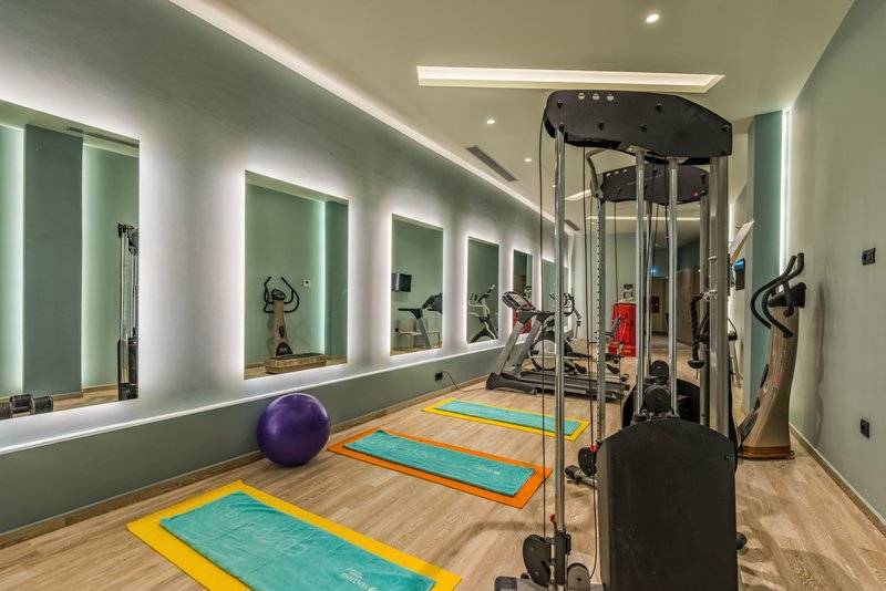 Fitnessraum im Alexandra Beach Resort mit Spiegeln, Trainingsgeräten und Yoga-Matten.
