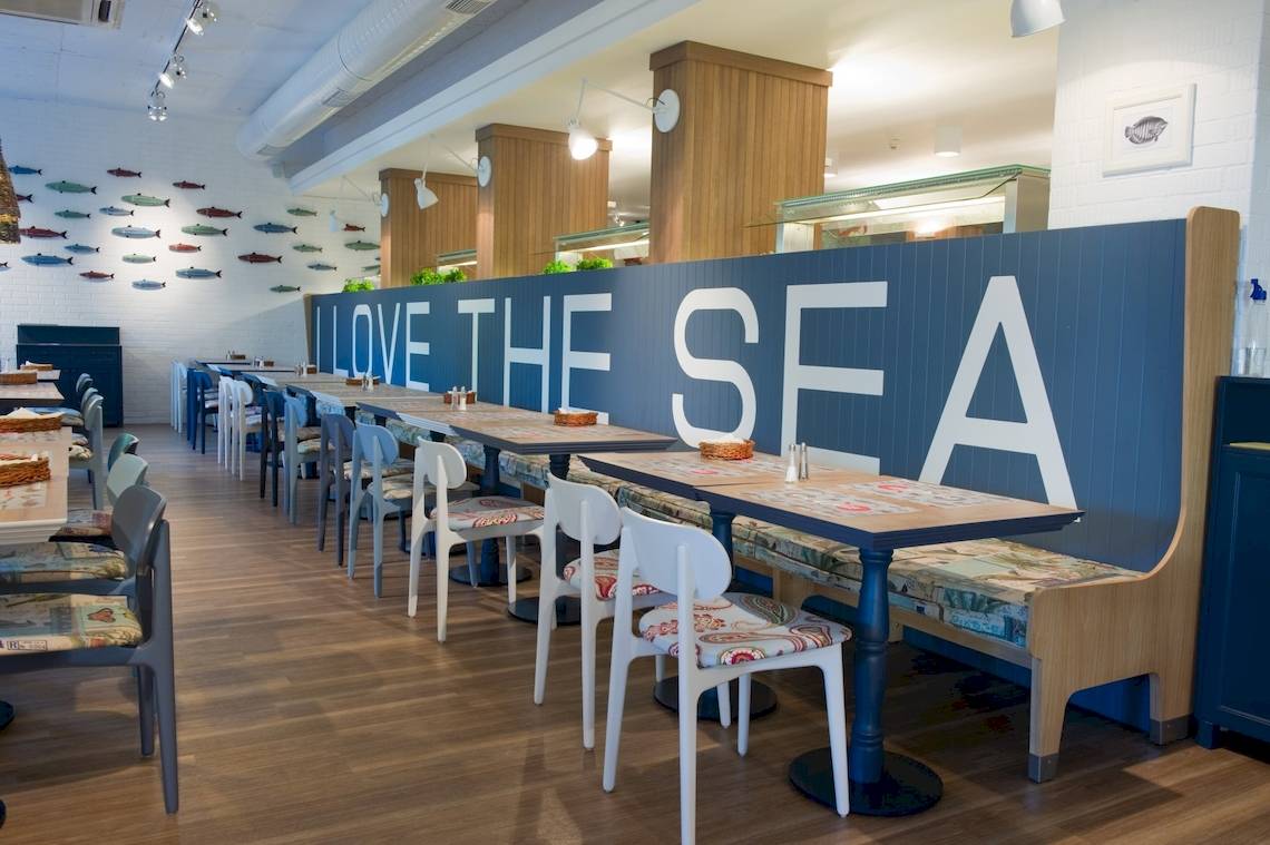 Innenansicht des Restaurants im Excelsior Hotel mit Tischreihen und der Wandbeschriftung 'LOVE THE SEA'.