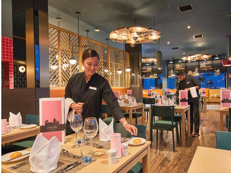 Ein Mitarbeiter des RIU Atoll Hotels bereitet einen Tisch in einem Restaurant vor.