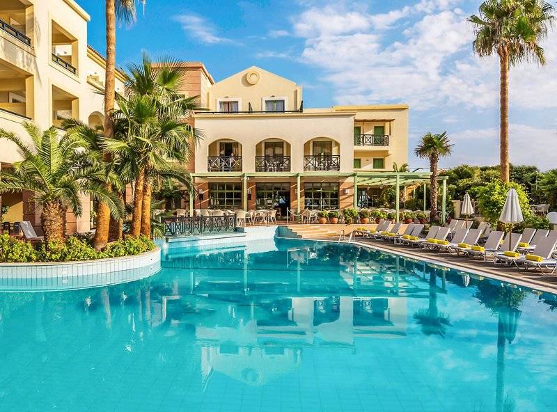 Außenbereich des Samaina Inn Hotels mit Swimmingpool, Palmen und Sonnenliegen.