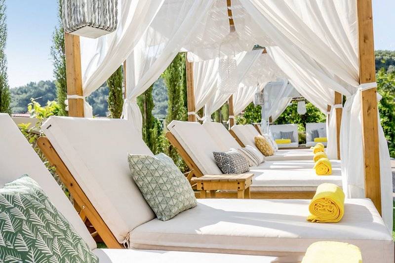 Reihe von weißen Lounge-Sesseln mit gelben Handtüchern unter einem weißen Vordach im Freien, Samaina Inn.