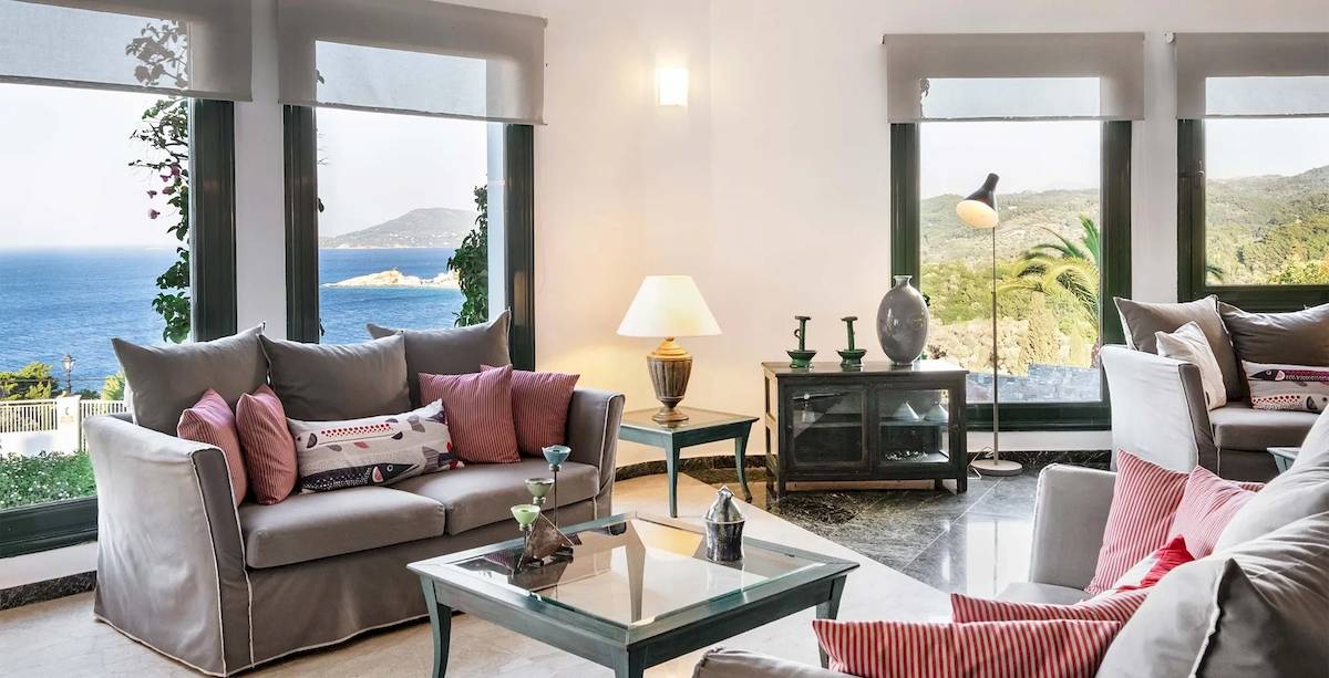 Wohnzimmer im Kalidon Panorama Hotel mit Meerblick, großen Fenstern und modernen Möbeln.