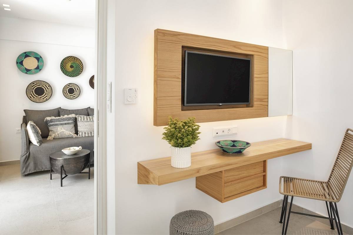 Innenansicht eines Hotelzimmers im Kalidon Panorama, mit einer Couch, Wanddekoration und Fernseher.