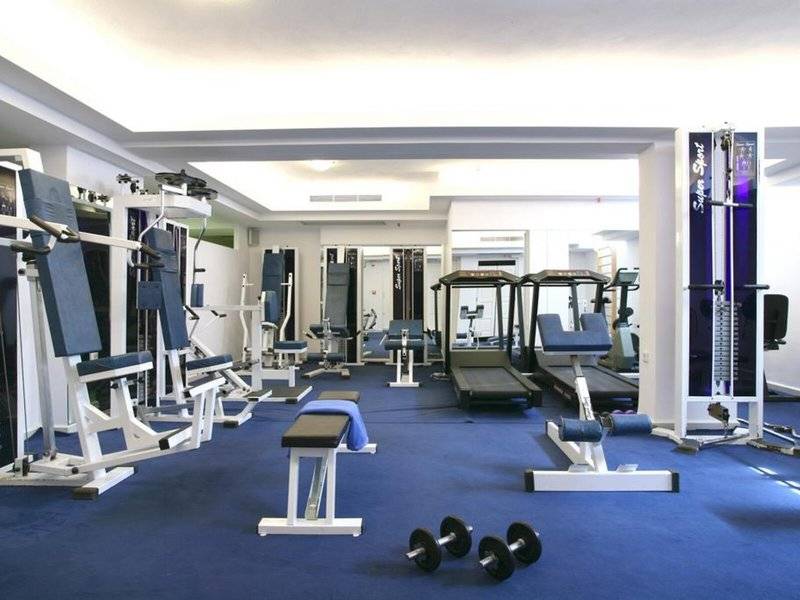 Fitnessstudio im Naxos Resort Beach Hotel mit verschiedenen Trainingsgeräten und einer blauen Trainingsfläche.