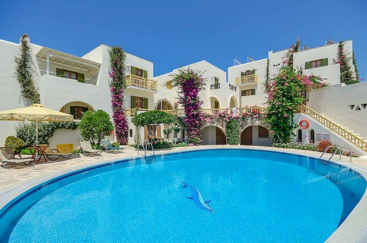 Außenpool des Proteas Hotel & Suites mit umliegenden Gebäuden und Sonnenschirmen.