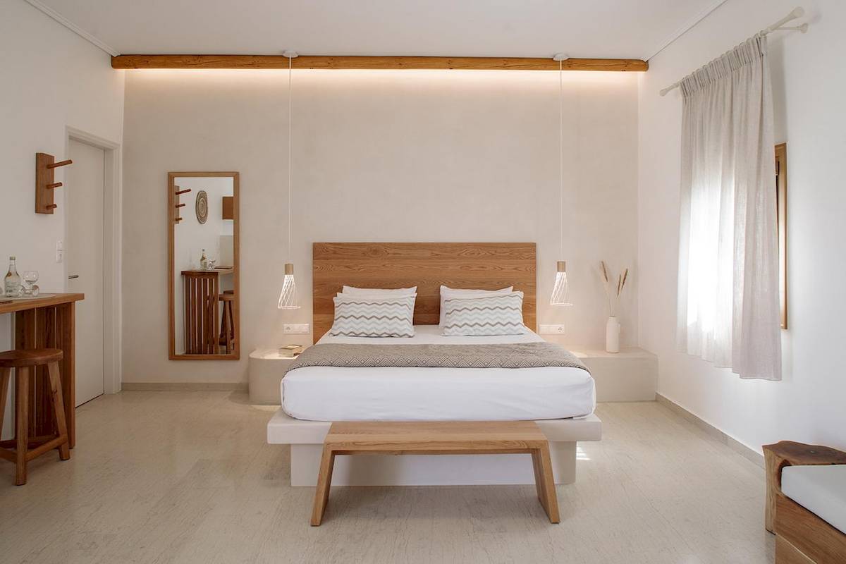 Schlafzimmer im Proteas Hotel & Suites mit weißem Bett, Holzkopfteil und hölzerne Möbel.