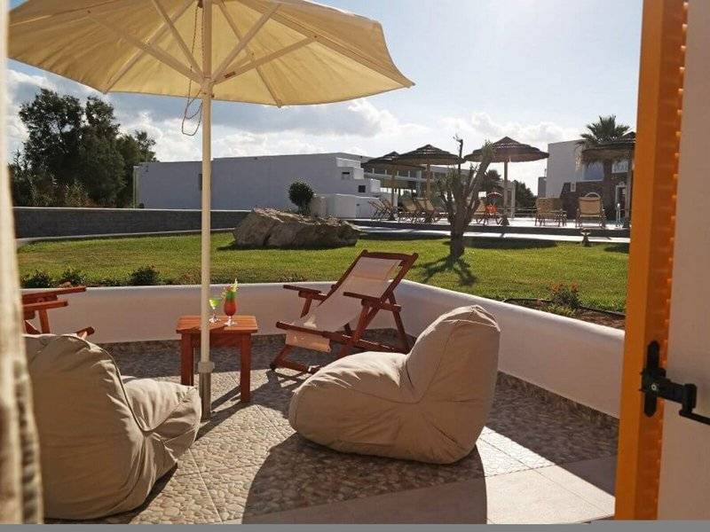 Außenbereich des Aegean Palace Hotels mit Loungestühlen, Kissen und Sonnenschirmen auf der Terrasse.