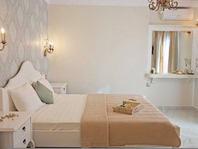 Schlafzimmer im Aegean Palace Hotel mit einem Bett, weißen Möbeln und einem Spiegel.