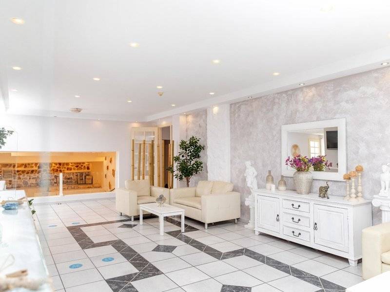 Das goldene Coast Hotel mit weißem Interieur, zwei Sofas, einem Tisch, einem Spiegel und einem Pflanzentopf.