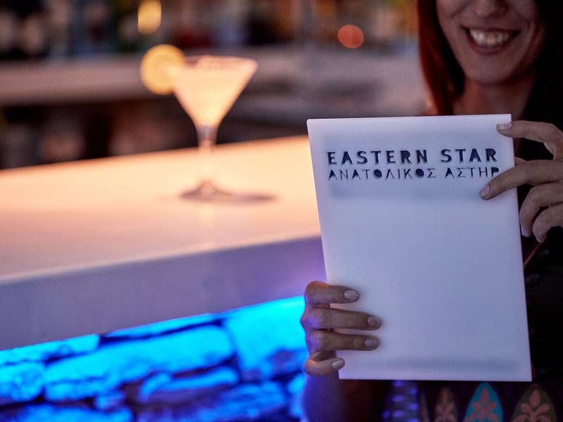 Frau die eine Eastern Star Karte bei einem Cocktail hält.
