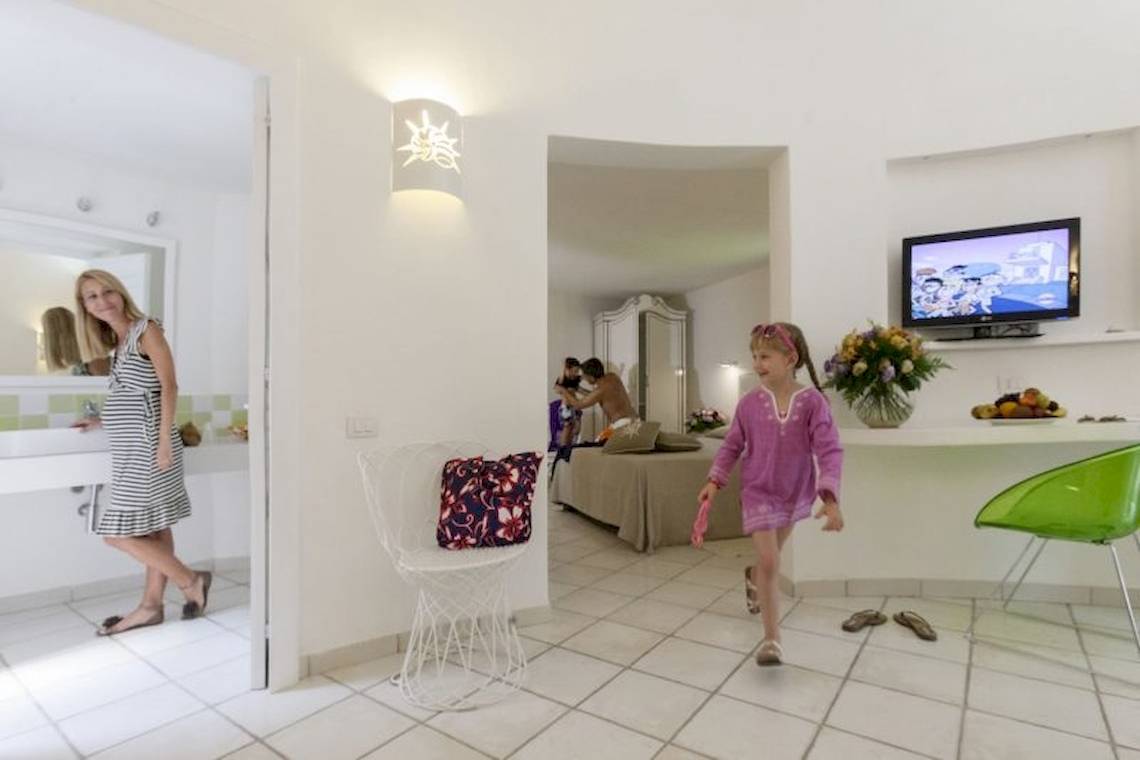 Frau und Mädchen im Mare Pineta Hotelzimmer neben einem Fernseher und Bett