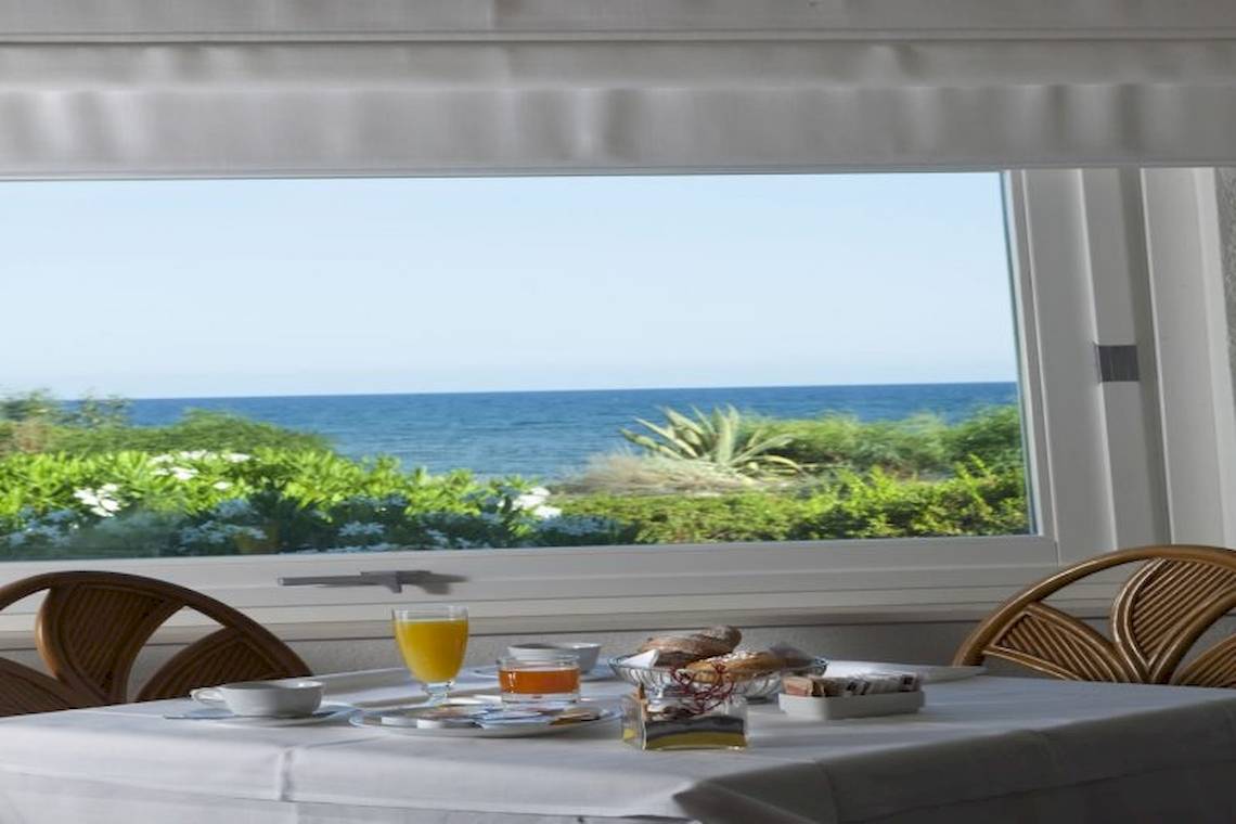 Frühstückstisch im Mare Pineta mit Blick auf das Meer und die Pflanzen.
