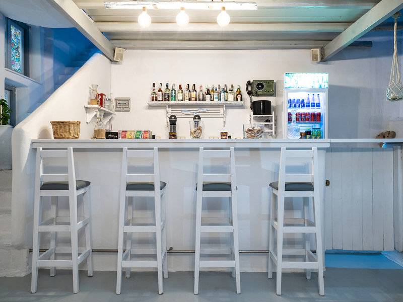 Barbereich des Iris Boutique Hotels mit weißen Stühlen und Theke.