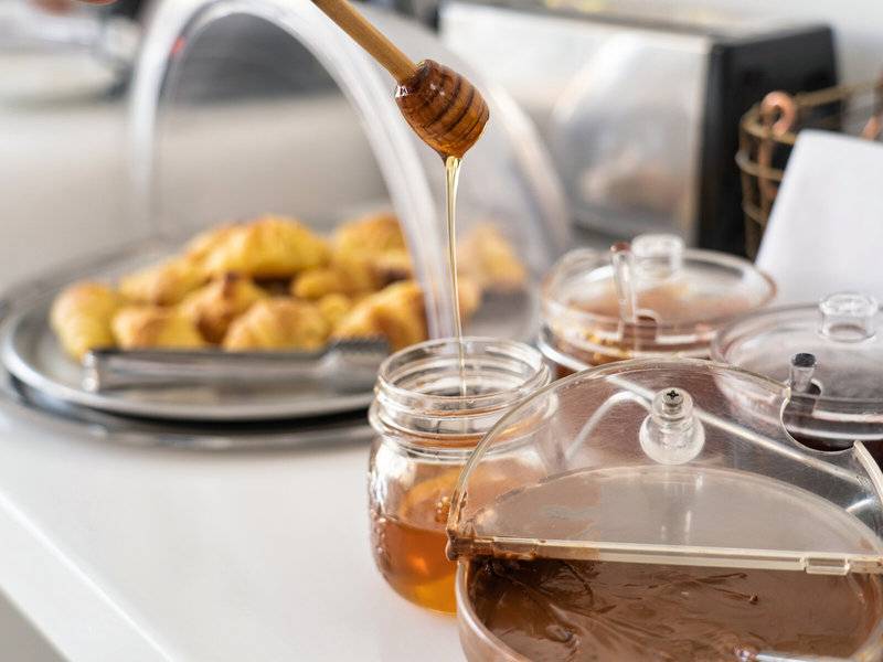 Ein Honigtopf wird über Frühstücksgebäck im Iris Boutique Hotel gegossen.