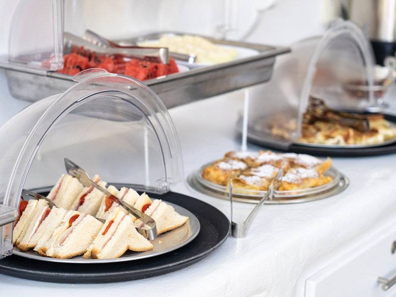 Frühstücksbuffet im Iris Boutique Hotel mit Sandwiches, Früchten und Waffeln.
