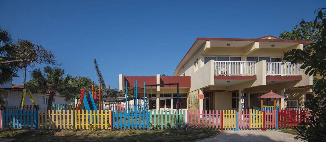 Außenansicht des Gran Caribe Villa Tortuga Hotels mit buntem Spielplatz davor.