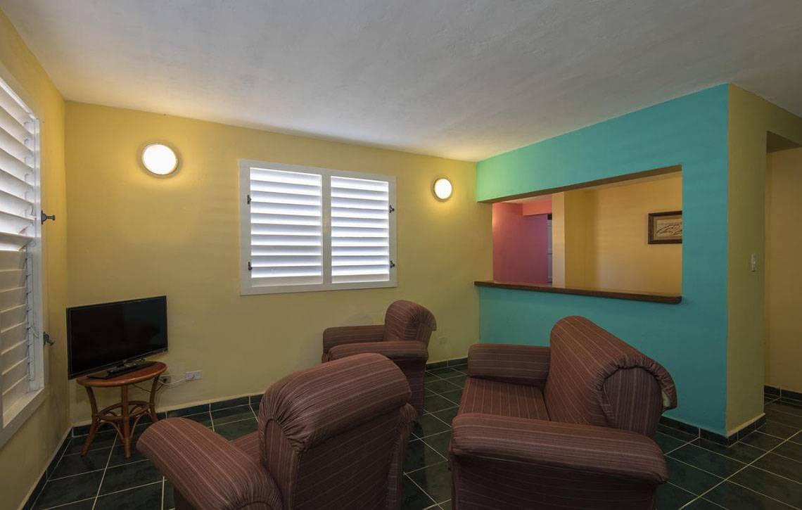 Wohnzimmer im Gran Caribe Villa Tortuga Hotel mit Fernseher und Sesseln.