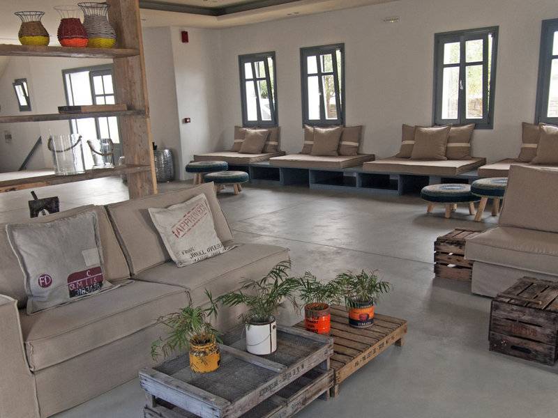 Poseidon of Paros Hotel & Spa Lounge mit Sofas, Kissen, Tischen und Pflanzen.
