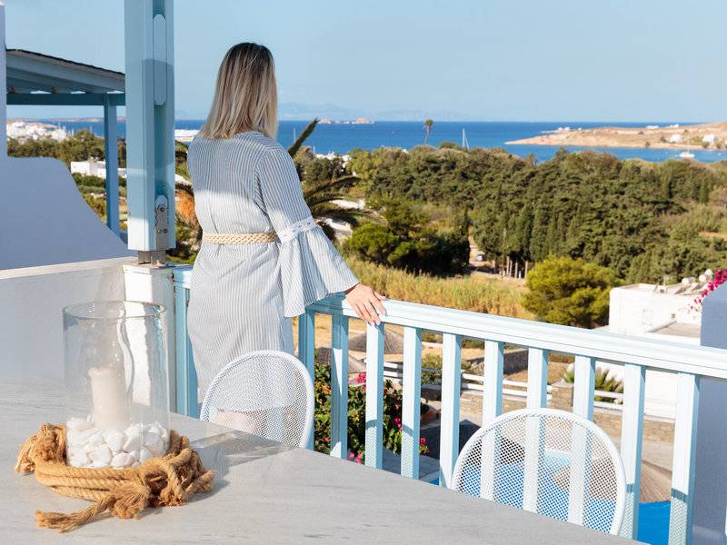 Eine Frau mit blonden Haaren genießt die Aussicht auf das Meer vom Balkon des Pyrgaki Hotels.